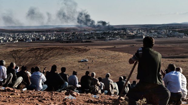 Natural grandstand: Kurdish people watch the battle for the Syrian town of Kobane from a hill in neighbouring Turkey.