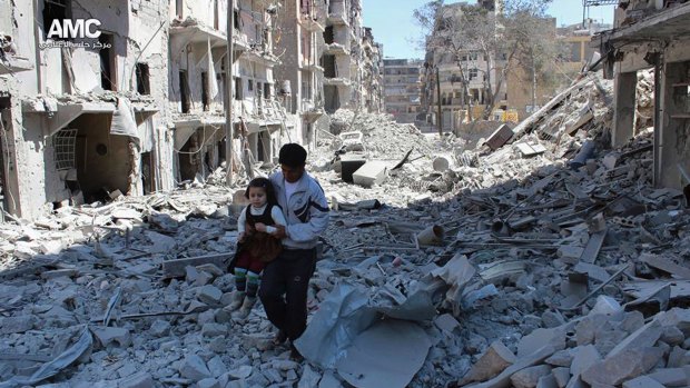 A photo from the anti-government Aleppo Media Centre shows a Syrian man holding a girl as he stands on houses destroyed by  air strikes in the city.