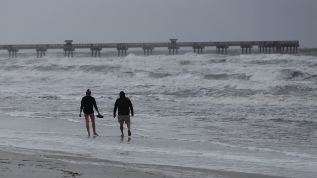 A man and a woman walk on the beach in Jacksonville Beach, Florida. 
