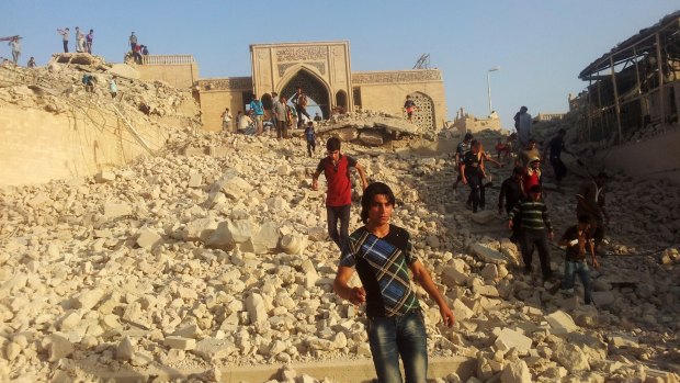 People walk through the rubble of the Prophet Younis Mosque in the city of Mosul. According to an opinion poll, support for IS has grown markedly in the city  in the past six months.