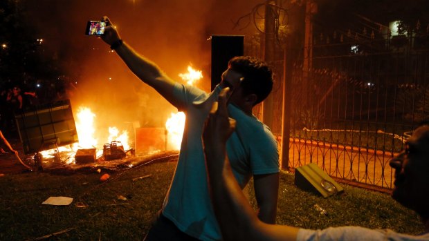 Two men pose for selfies during a protest against presidential re-elections at Congress, in Asuncion, Paraguay, on Friday, March 31, 2017.