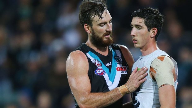 Port Adelaide's Charlie Dixon celebrates the win but consoles a dejected Jacob Weitering.