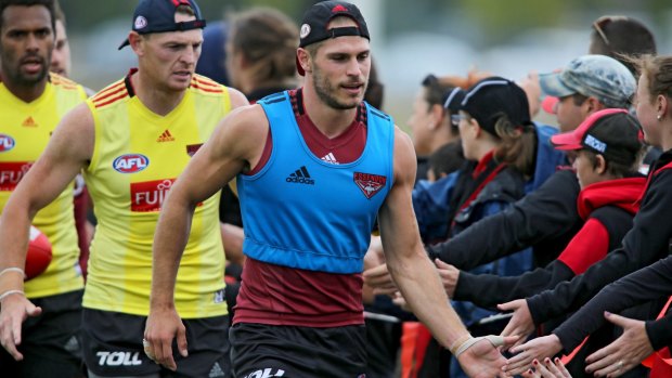 Essendon players run past fans at training.