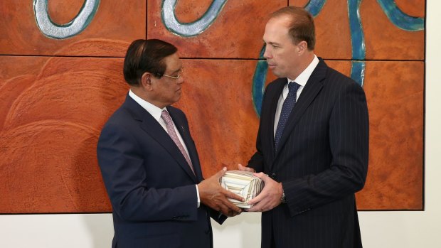Immigration Minister Peter Dutton gives a present to Cambodian Deputy Prime Minister and Minister of the Interior Sar Kheng, during a signing of a memorandum of understanding.