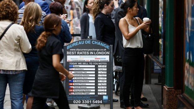 Customers queue outside a foreign currency exchange bureau in London.