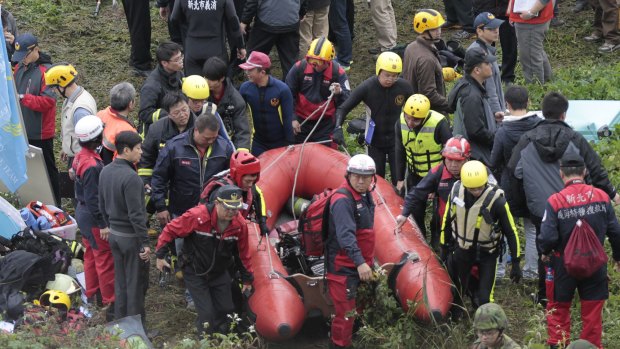 Emergency personnel carry an inflatable dinghy to try to extract passengers from the plane after it crashed in a river in Taipei.