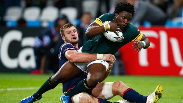 Lwazi Mvovo of South Africa goes over to score their tenth try as he is tackled by Cam Dolan of the United States.