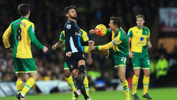 Up it goes: Olivier Giroud and Gary O'Neil battle for the ball at Carrow Road.