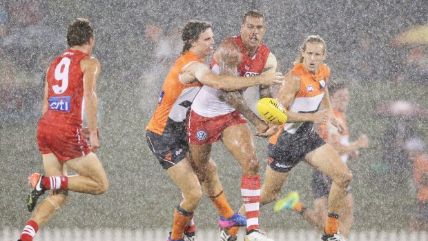 Lance Franklin is nabbed by Callan Ward during a downpour at Blacktown on Friday night.