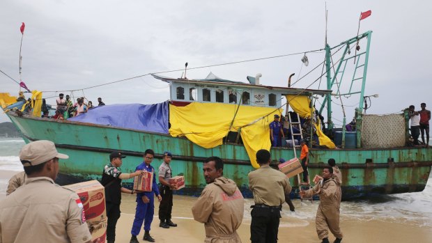 Indonesian officials load food supplies onto a boat carrying Tamil migrants stranded on the beach in Lhoknga.