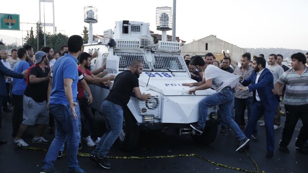 People try to stop a Turkish police armoured vehicle carrying soldiers that participated in the coup and surrendered on Saturday.