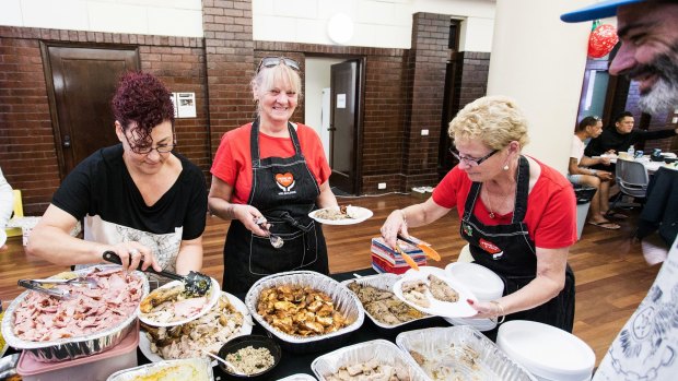 Putting smiles on their dials: Ms Henry and fellow volunteers serve Christmas lunch to the disadvantaged at the Drill Hall in Therry Street.