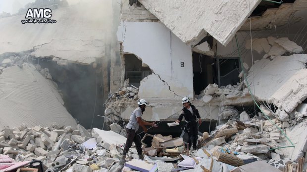 Syrian civil defence workers inspecting ruined buildings after regime air strikes in the city in August.