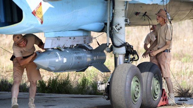 Russian military support crew attach a satellite-guided bomb to a jet fighter in Syria. 