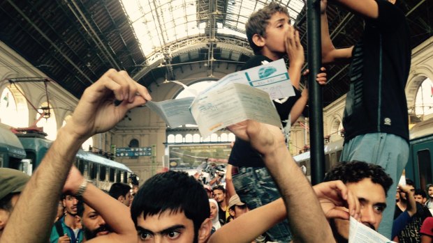 Migrants show their tickets at Budapest station, demanding to be let on a train to Germany. 
