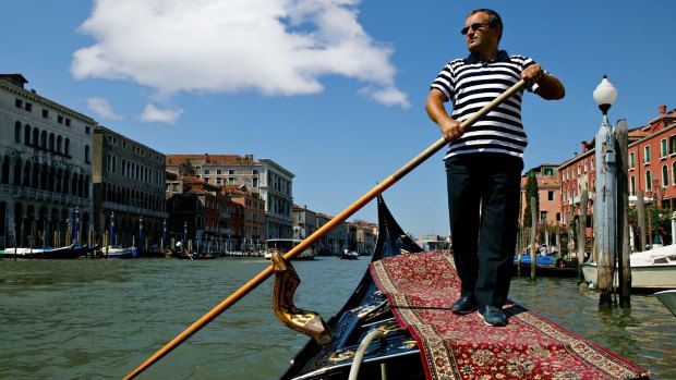 A gondolier guides his craft along the Grand Canal of Venice.