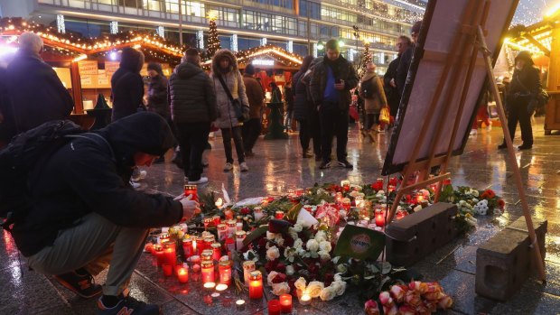  A visitor lays a candle at a makeshift memorial inside the reopened Breitscheidplatz Christmas market.