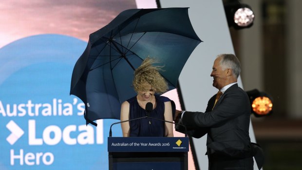 Local Hero of the Year Catherine Keenan is shielded by Prime Minister Malcolm Turnbull at a windy Parliament House.