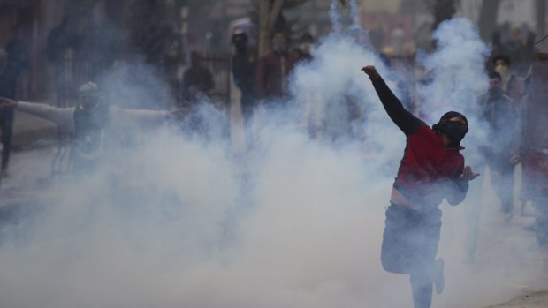 A protester throws back an exploded tear gas shell in Indian controlled Kashmir on Friday. Experts say tight security along the disputed frontier has pushed the focus of militant activity south.