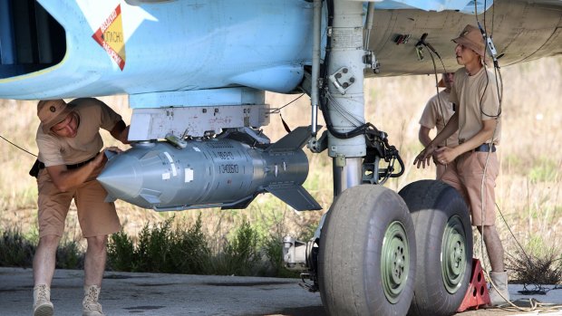 Russian military support crew attach a satellite-guided bomb to a jet fighter in Syria.