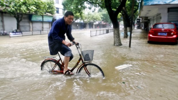 A resident rides a bicycle on a flooded road in Xiangshan county, Zhejiang province.