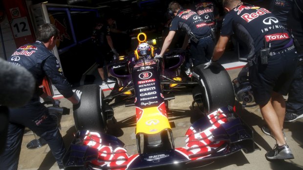 Mechanics push the vehicle of Red Bull's Daniel Ricciardo of Australia into the box during the third free practice of the Spanish Grand Prix.