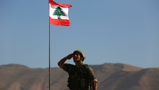 A Lebanese soldier salutes the national flag atop an armoured personnel carrier on the outskirts of Ras Baalbek, north-east Lebanon.