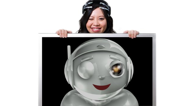 Le wearing the original EPOC headset that senses her smile and wink, causing a computer-generated cartoon robot to mirror her expression. 