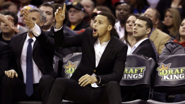 Sidelined: Golden State Warriors' Stephen Curry yells to teammates as he sits on the bench, out with a bruised leg.