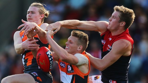 Tom McDonald, of the Melbourne Demons, and Cam McCarthy and Adam Treloar, of the Greater Western Sydney Giants, tussle for the ball during the round two AFL match at Startrack Oval, Manuka. 