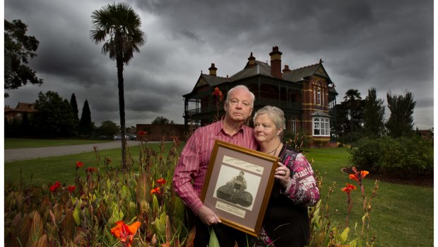 David Campbell and sister Pauline Shugg hold a picture of their late WWII POW father, Pat Campbell, in front of Bundoora Homestead, the reception block of the veterans' mental hospital where Pat was a patient for 21 years. 