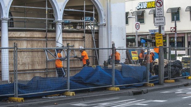 Workers remove scaffolding from the building at the corner of London Circuit and East Row