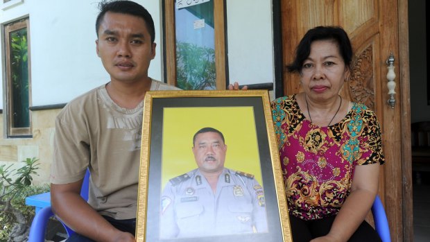The widow of Wayan Sudarsa, Ketut Arsini, and her son Kadek Toni, hold a portrait of the police officer who was killed on Legian beach. 