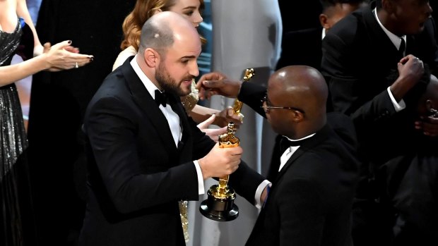 <i>La La Land</i> producer Jordan Horowitz, left, hands over the best picture award to <i>Moonlight</i> writer-director Barry Jenkins.