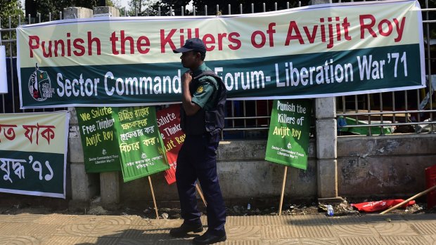 A Bangladeshi policeman walks past a banner for slain US blogger Avijit Roy during a protest in Dhaka.