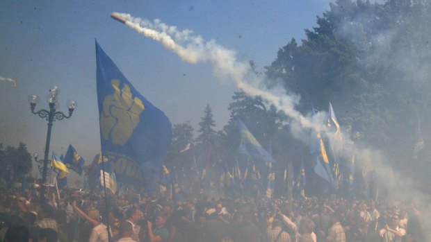 A smoke grenade is thrown towards police during protests in Kiev.