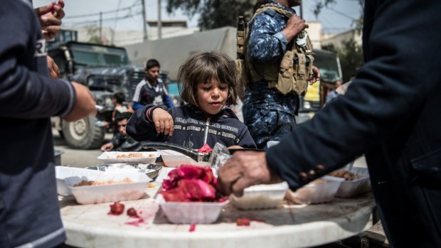 A girl eats food distributed by volunteers in west Mosul.