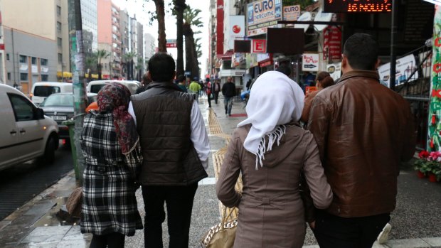 The couples walk along the street in the Turkish city of Izmir, where supplies for the Aegean Sea crossing are sold.