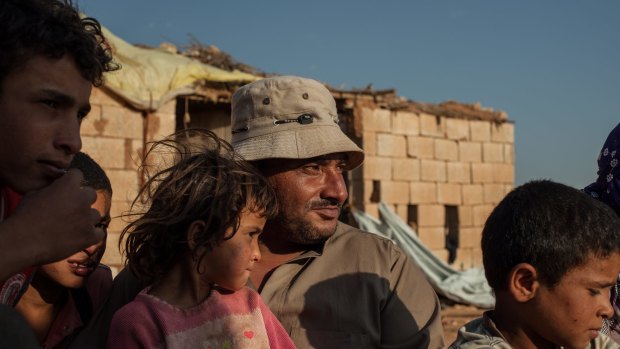 Mohamed Ahmad, 35, sits with his family outside a disused farm building they now share in Turkey after fleeing their home town of al-Fwaida in Syria's Hasaka province.