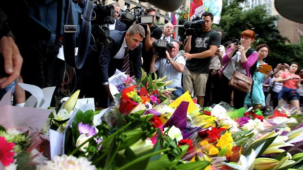 NSW Premier Mike Baird lays flowers at Martin Place after the siege.