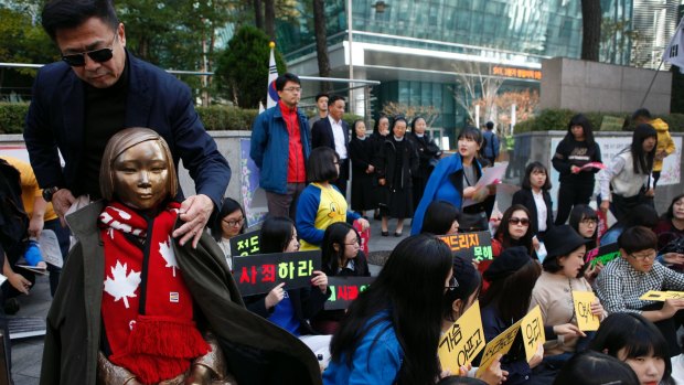 An activist put his coat on a Comfort Woman statue before protests in front of Japanese embassy in Seoul in 2014.