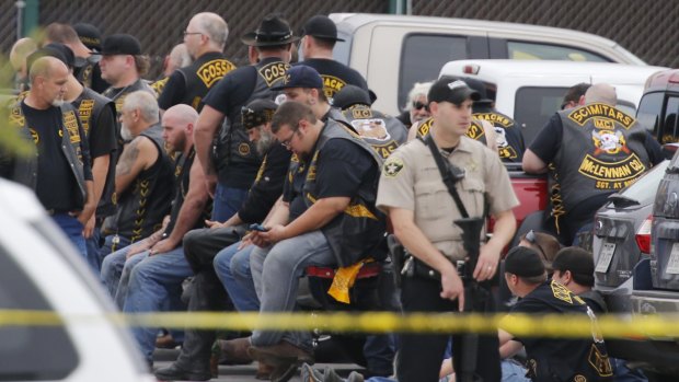 A McLennan County deputy stands guard near a group of bikers in the parking lot of a Twin Peaks restaurant.