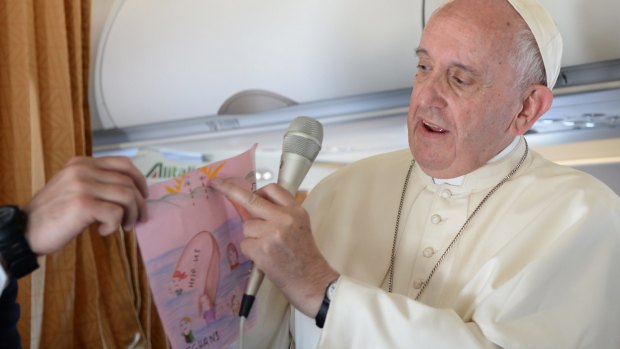 Pope Francis shows drawings made by children on his flight back to Rome.