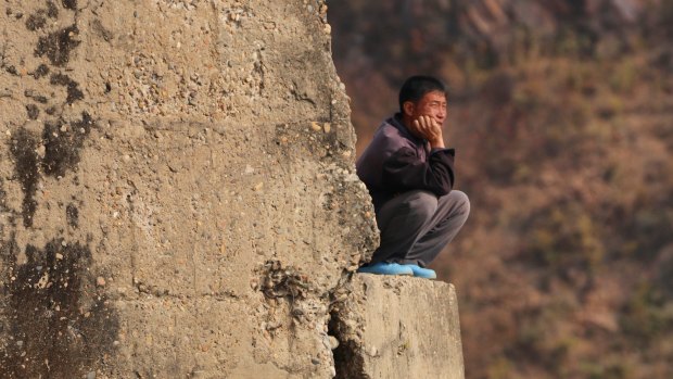 A North Korean man in deep thought on the bank of Yalu River.