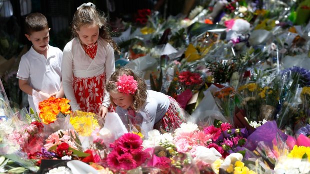 A girl adds flowers to the tributes at Martin Place.