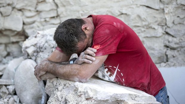 A man leans on rubble following the earthquake in Amatrice.