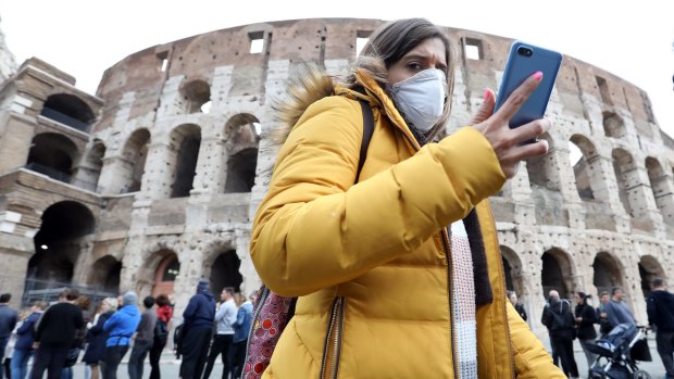A pedestrian wearing a protective face masks walks past the Colosseum in Rome, Italy, on Tuesday, Feb. 25, 2020. Italy appears never far from a recession, and the spread of the coronavirus may just tip it back into the danger zone. Photographer: Alessia Pierdomenico/Bloomberg