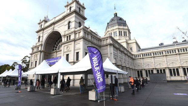 People wait in the 'walk ins' queue for COVID-19 vaccinations at the Royal Exhibition Building.