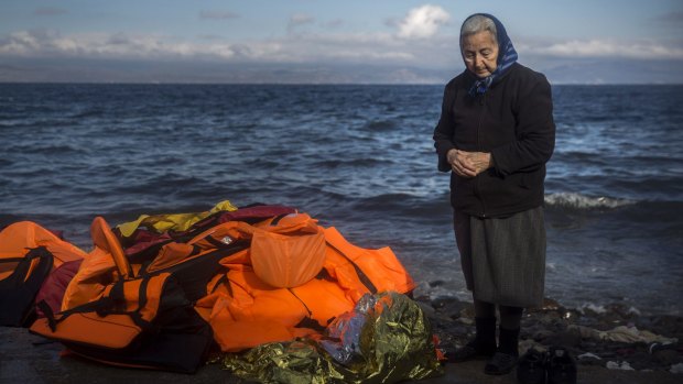 A local stands next to a pile of discarded life jackets after the arrival of refugees and migrants to the Greek island of Lesbos.