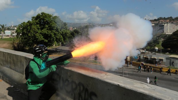 An anti-government demonstrator fires a mortar at security forces blocking an opposition march.
